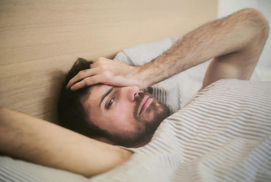 A person waking up tired in bed despite a full night’s sleep, illustrating the frustration of persistent fatigue.